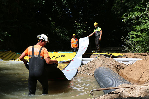 The flexible DP-3075 discharge hose, 450mm in diameter, is attached to the Water-Gate © weir. Then we roll out completely downstream before filling the water.