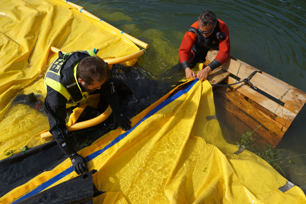 Équipe rallongeant un batardeau Water-Gate avec planche d’appui en berge